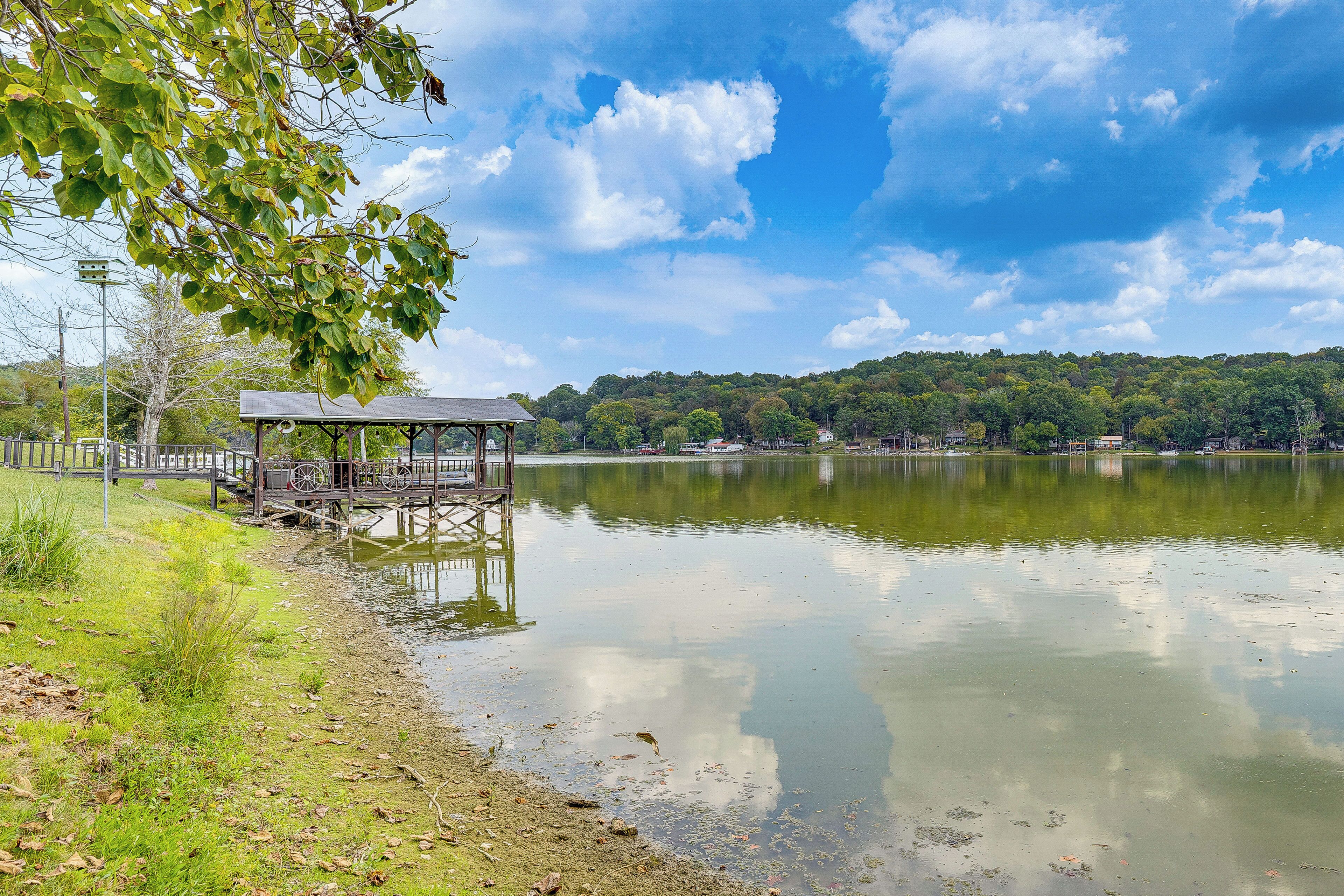 A lakeside gazebo with a view of a forested hill.