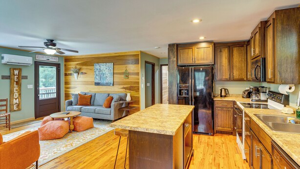 A modern kitchen with wooden cabinets, a built-in refrigerator, and a bar area. - Peaceful Cabin at Lake Logan w/ Spacious Yard! (Ardmore)