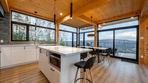 Una cocina moderna con una isla central, ventanas amplias y un comedor con vistas.