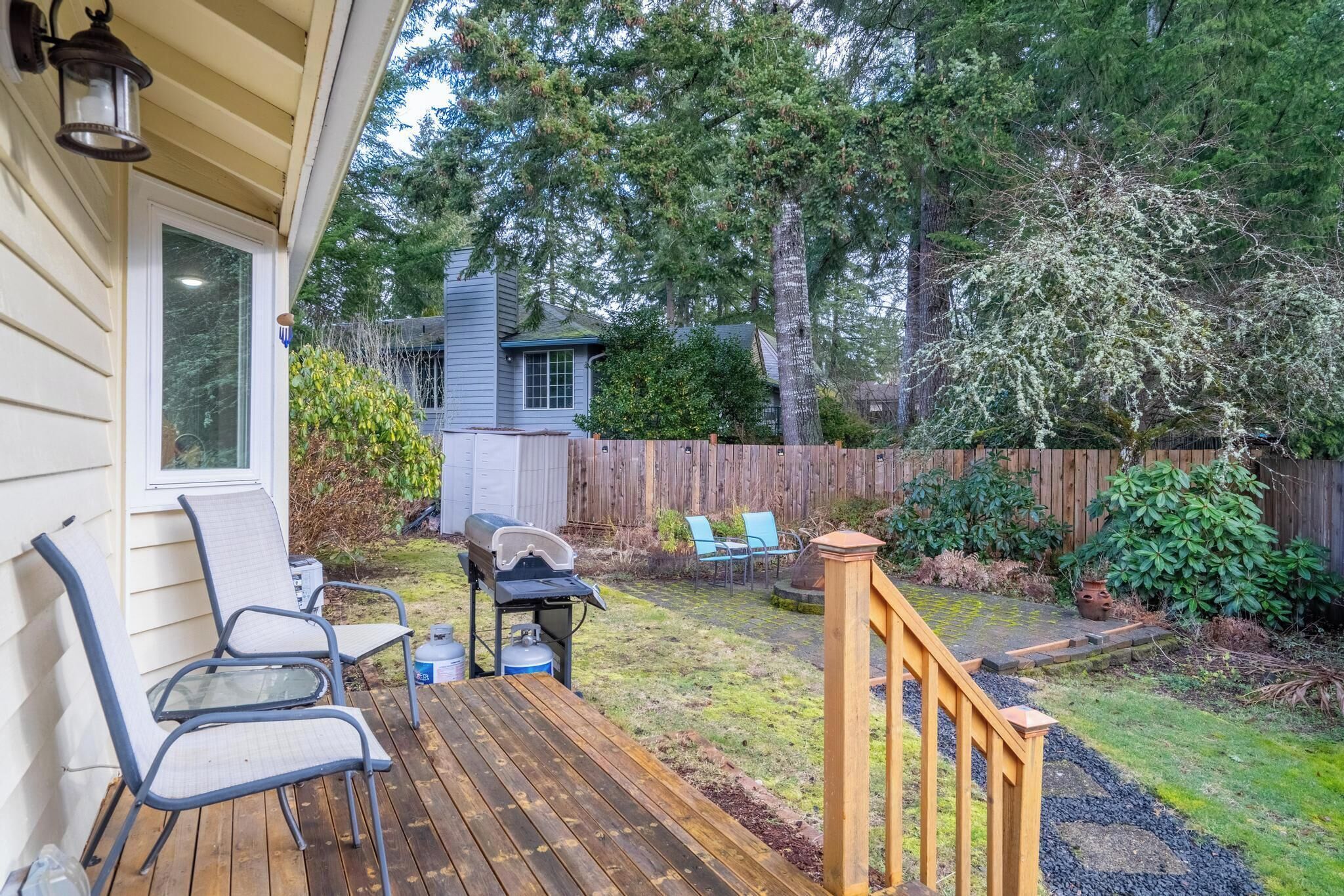 A wooden deck with outdoor furniture, a barbecue grill, and a wooden fence.