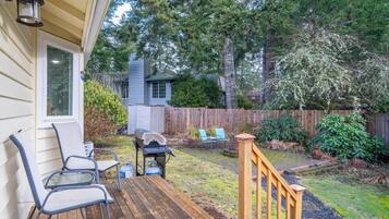 A wooden deck with outdoor furniture, a barbecue grill, and a wooden fence.