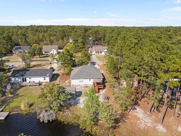 A residential area with houses, a dock, and a forested hill. - Lake Keziah House-Lake View, Spacious, & Private! (Southport)