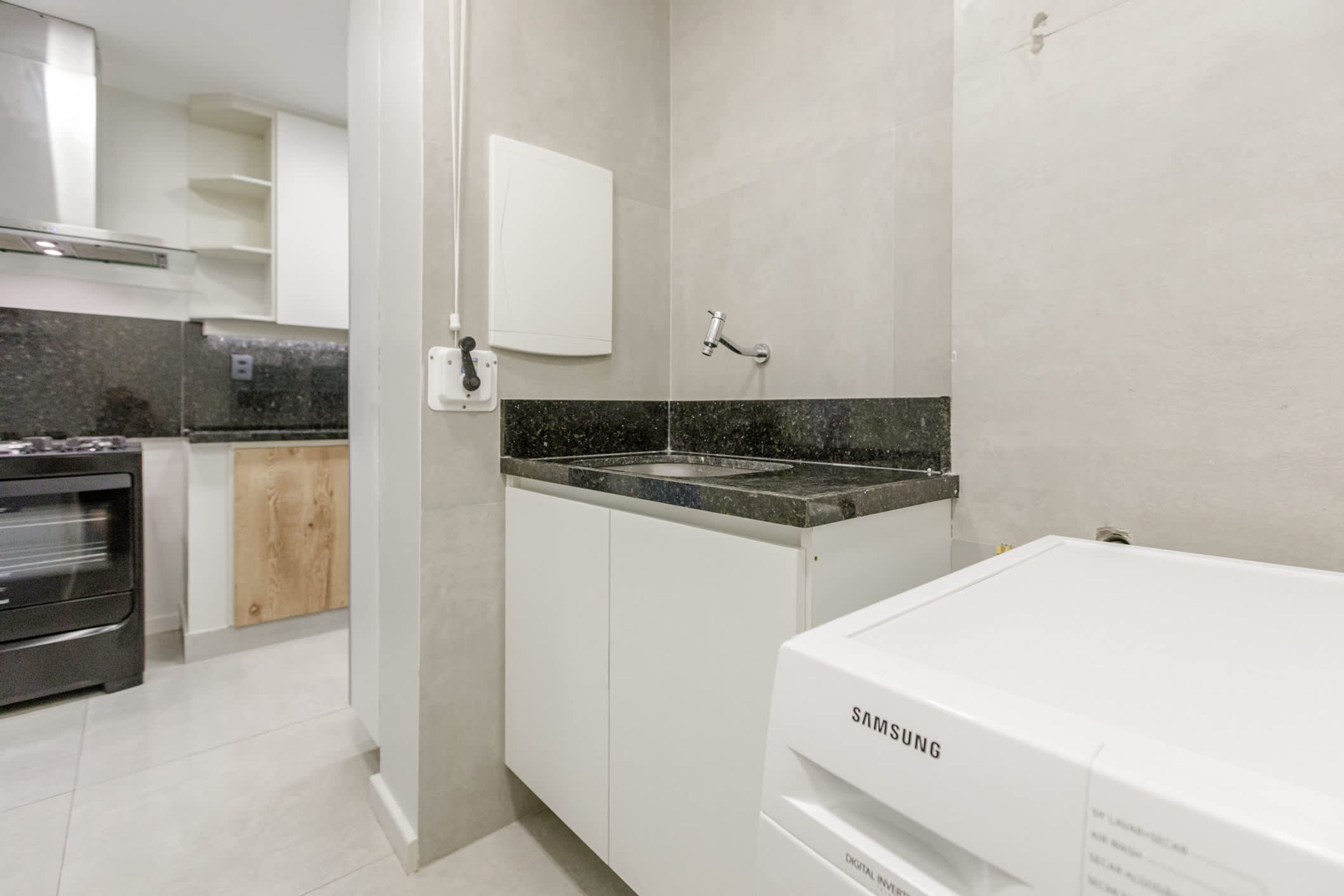 A modern kitchen with white cabinets, a granite countertop, and a built-in oven.