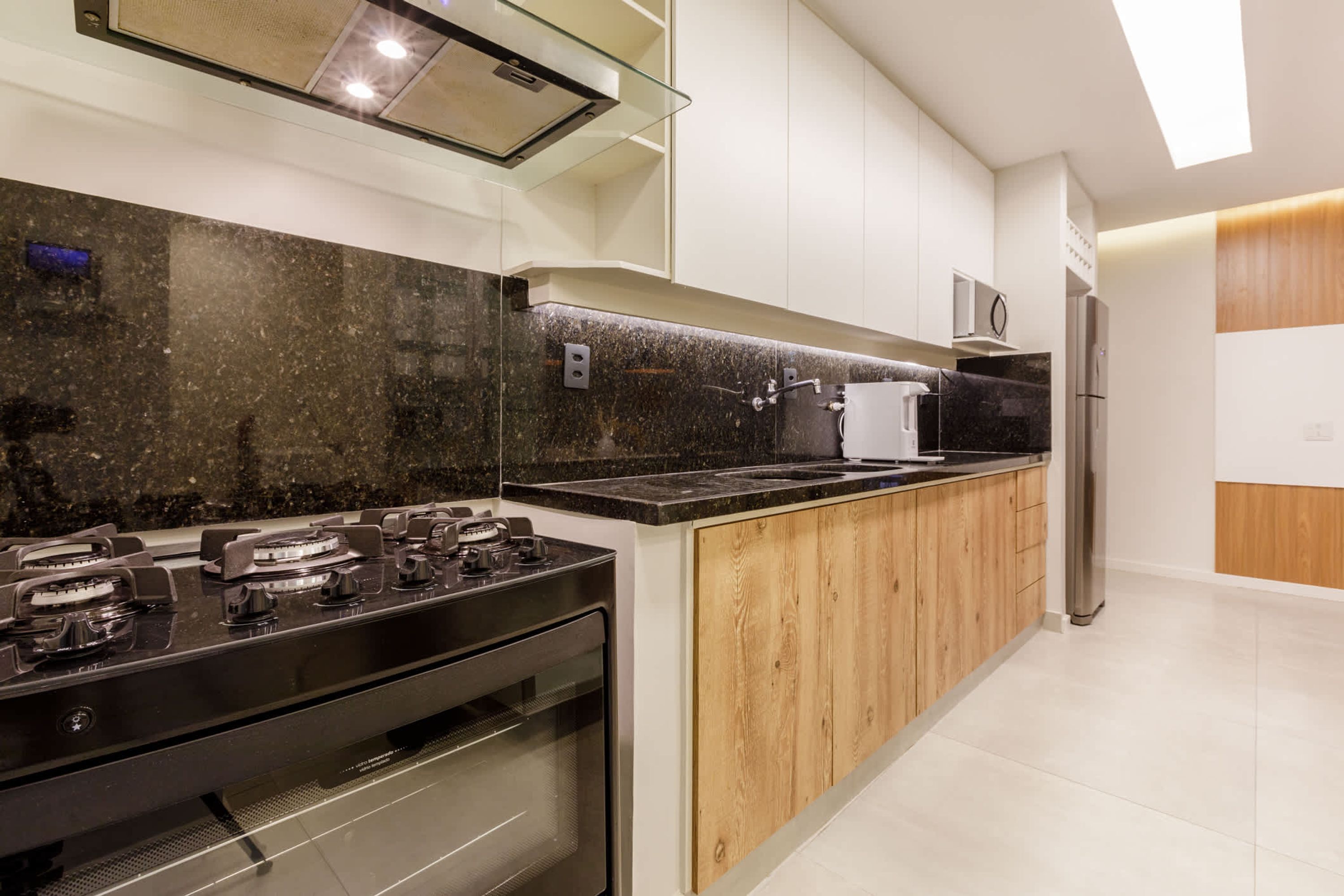 A modern kitchen with a black granite countertop, wooden cabinets, stainless steel appliances, and a built-in oven.