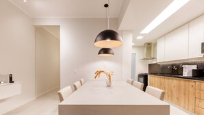 Une cuisine moderne dotée d’un grand îlot central, de meubles en bois et d’un luminaire suspendu.