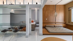Un interior moderno con una mesa de vidrio, sillas transparentes, una cama y un banco de madera.