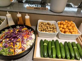A salad with various vegetables and a tray of cucumbers.