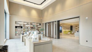 Un interno moderno con una reception, scaffali con prodotti e un'ampia vetrata.