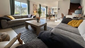 Un salon moderne avec un canapé, une table basse et un coin repas à l’arrière-plan.