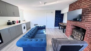 Una cocina moderna con armarios grises, lavadora integrada y un sofá modular azul.