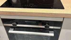Una cucina con piano cottura a induzione nero, forno integrato e piano di lavoro in legno.