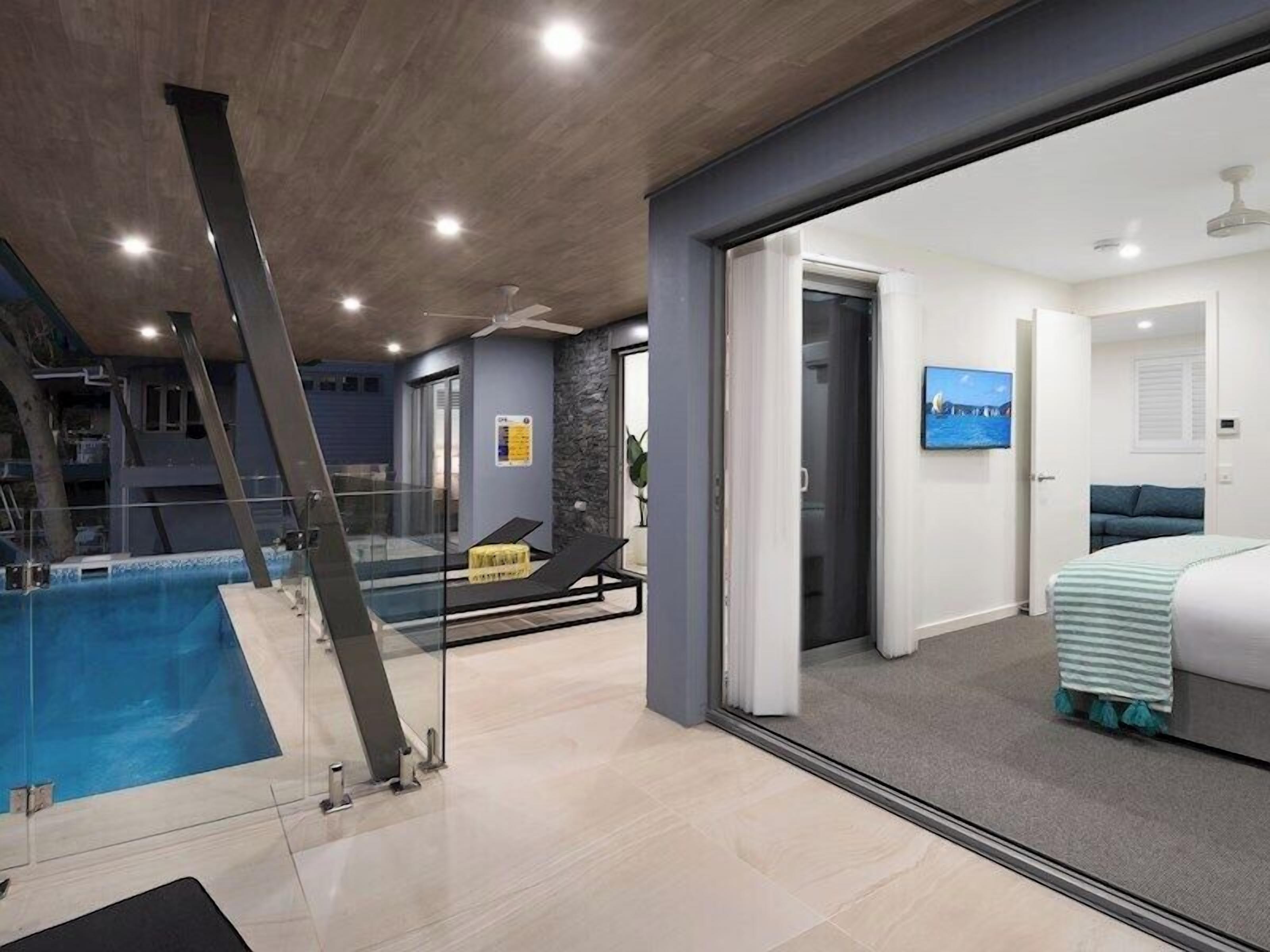 A modern hotel room with a glass door leading to a balcony overlooking a swimming pool.