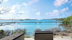 A balcony with a clear view of a large body of water and distant hills.
