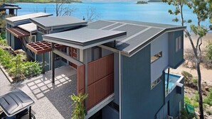 A modern house with a large deck, a pool, and a view of the water.
