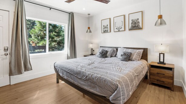 A bedroom with a bed, bedside tables, a ceiling fan, and framed pictures on the wall. - Zephyr Cove Unit 2 (Zephyr Cove)