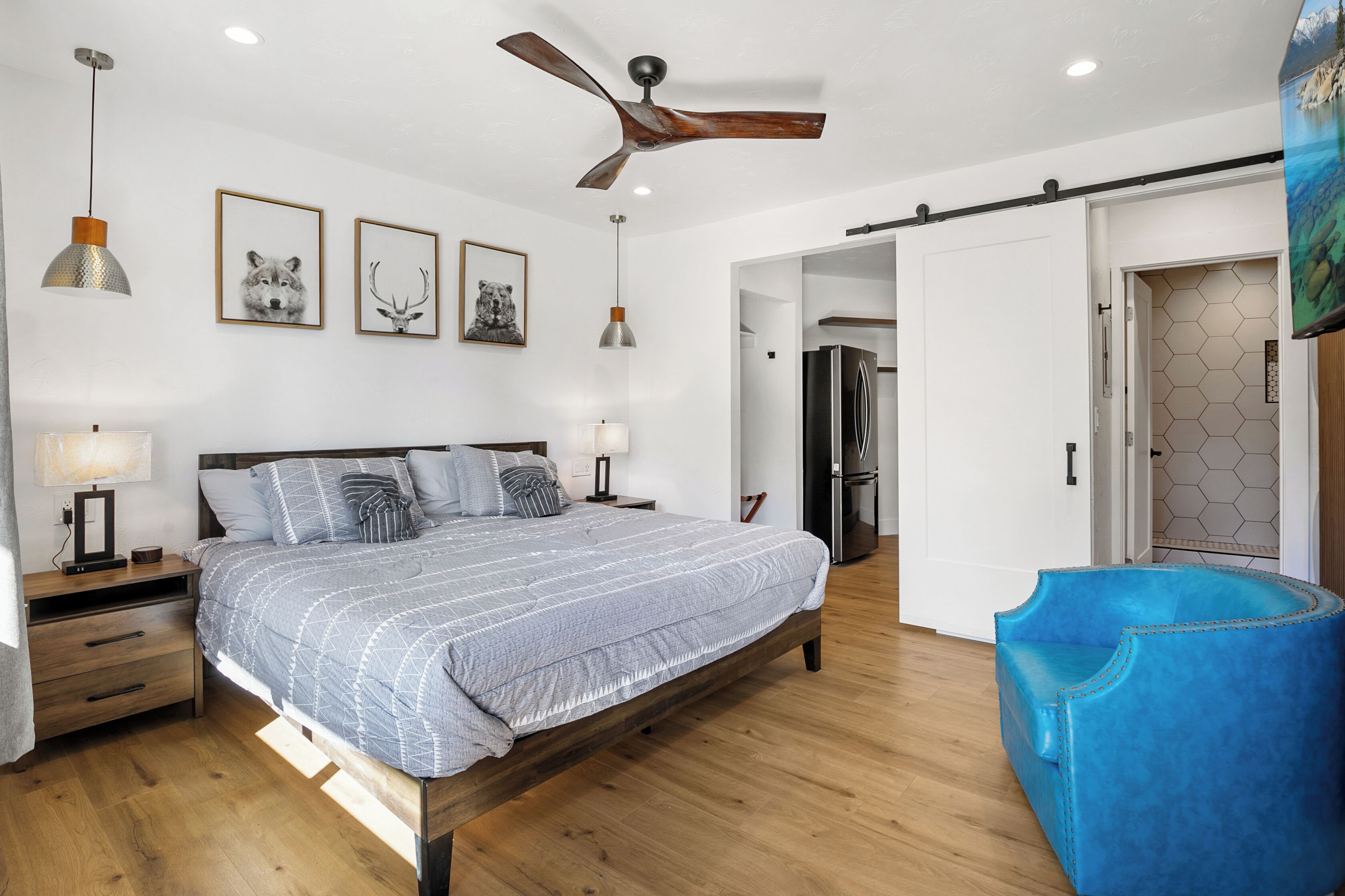 A modern bedroom with a wooden bed, a ceiling fan, and a blue chair.