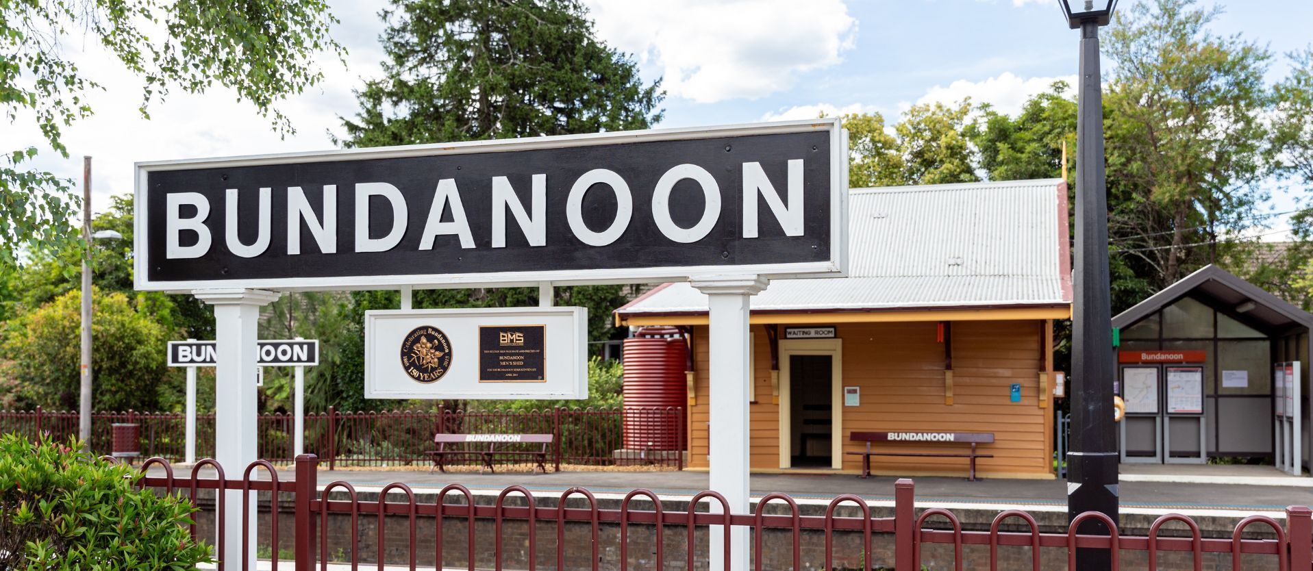 A sign for Bundanoon with a waiting room and a bench.