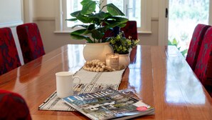 A wooden dining table with a magazine, a white mug, and a potted plant. - Balmaghie - charming, secluded 7 acre rural retreat in the Southern Highlands (Bundanoon)