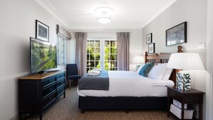 A hotel room with a large bed, a TV on a dresser, a desk with a lamp, and a window with curtains. - Balmaghie - charming, secluded 7 acre rural retreat in the Southern Highlands (Bundanoon)