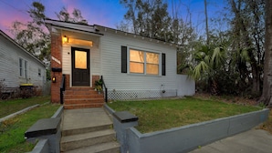 A single-story house with a front porch, a brick entrance, and a small front yard. - C.a.l.m. Cottage At The Last Mile 2 Bedroom Home (Savannah)