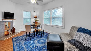 A living room with a dining area, a ceiling fan, a TV, and a fireplace. - C.a.l.m. Cottage At The Last Mile 2 Bedroom Home (Savannah)