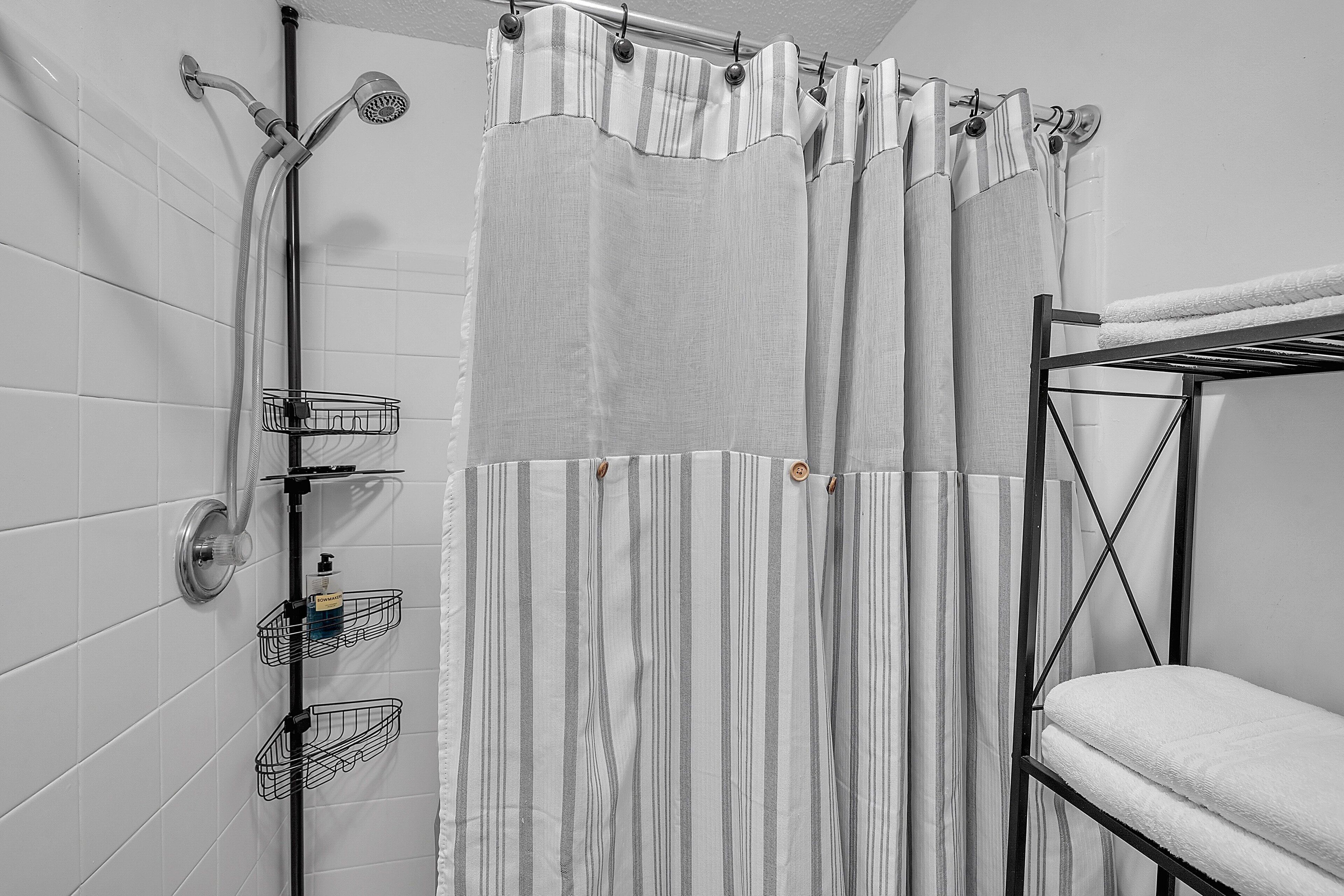 Ein Badezimmer mit Dusche, Handtuchhalter und einer gestreiften Duschvorhang.