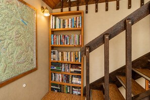 A wooden bookshelf filled with books, a large map on the wall, and a wooden staircase. - Icicle Chalet 1 Bedroom Cabin (Leavenworth)