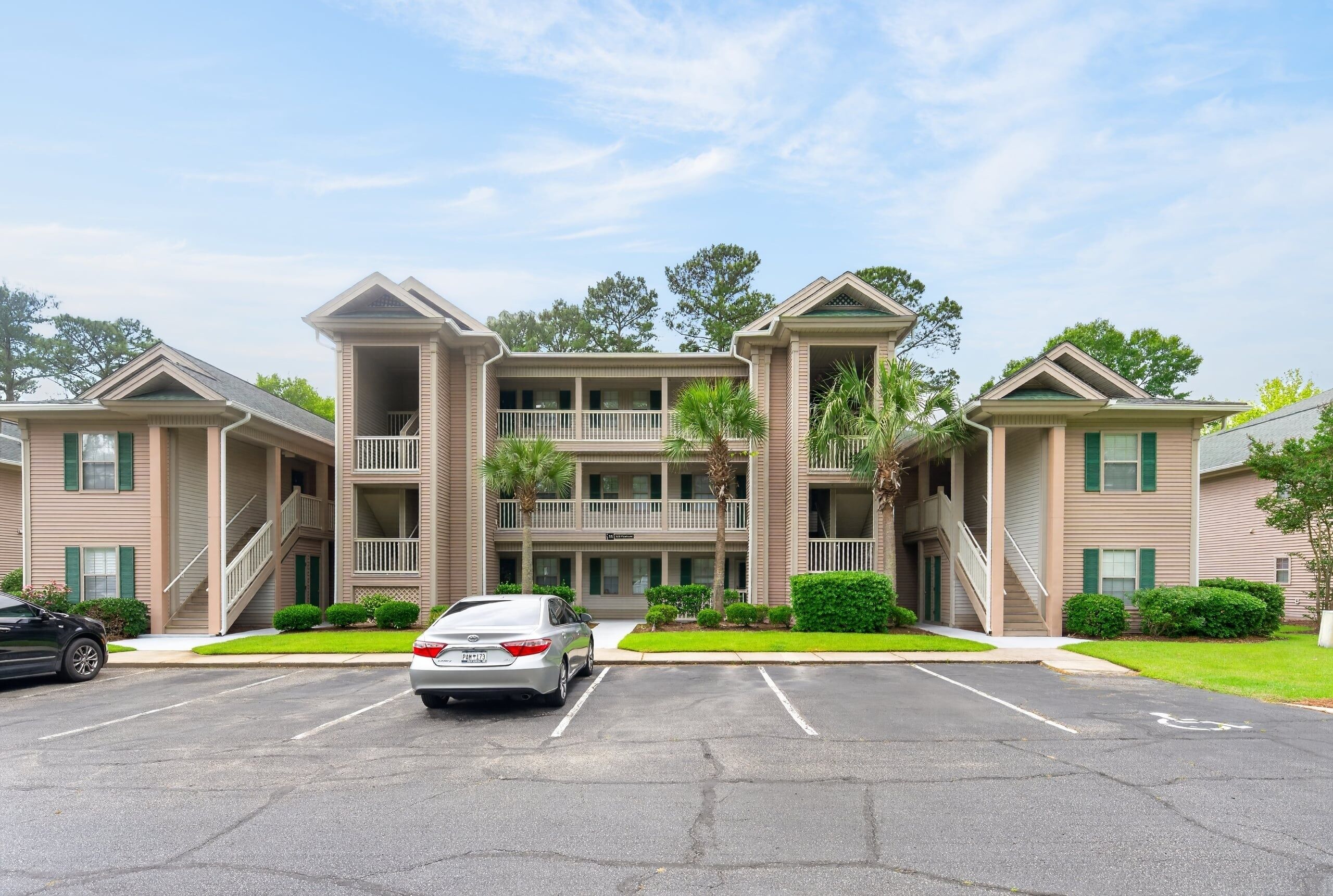 A multi-story hotel with a central atrium, balconies, and a parking lot.