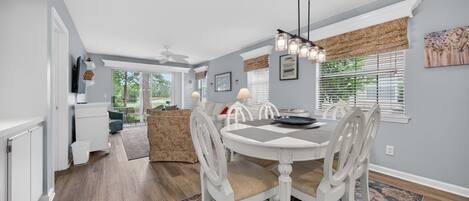 A dining area with a round table, white chairs, and a patterned rug.