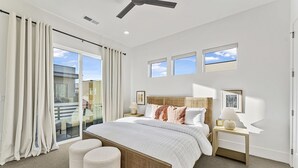A modern bedroom with a large bed, two bedside tables, a ceiling fan, and a view of the outside balcony. - Villa #35 At Bloomington Country Club 4 Bedroom Townhouse (St. George)