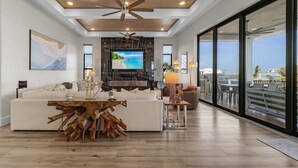 Un salon spacieux doté d’un grand téléviseur, d’un ventilateur de plafond en bois et d’un coin repas avec une table originale faite à partir d’une souche d’arbre.