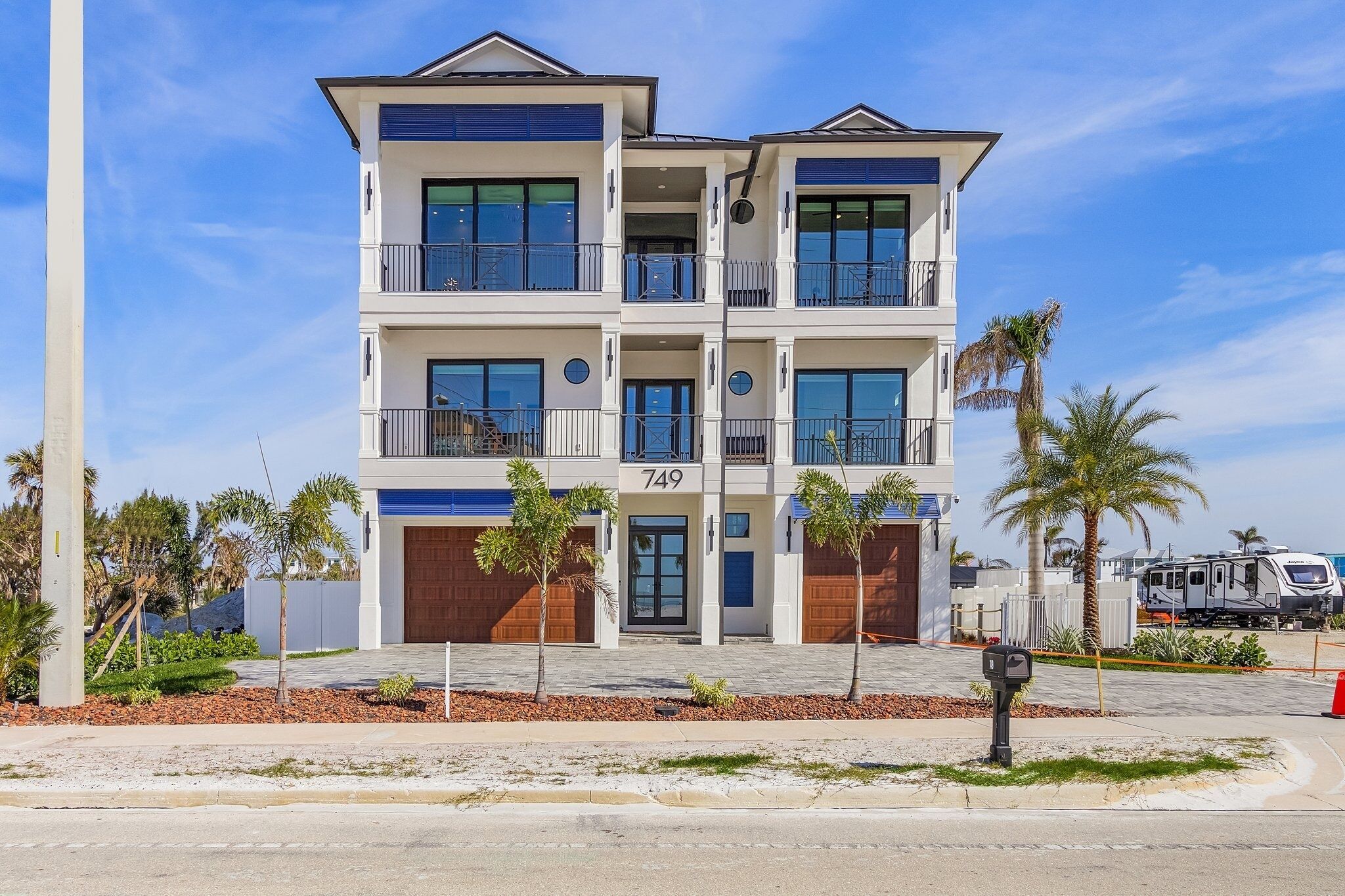 A multi-story residential building with balconies, a garage, and a clear view of the street.