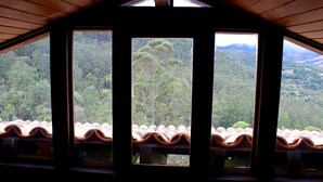 A room with a sloped ceiling and large windows offering a view of a forested landscape. - Itaipava House (Itaipava)
