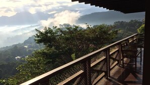A wooden deck with a metal railing overlooking a mountainous landscape. - Itaipava House (Itaipava)