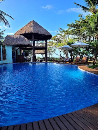 Una piscina al aire libre, sombrillas, sillones reclinables de piscina