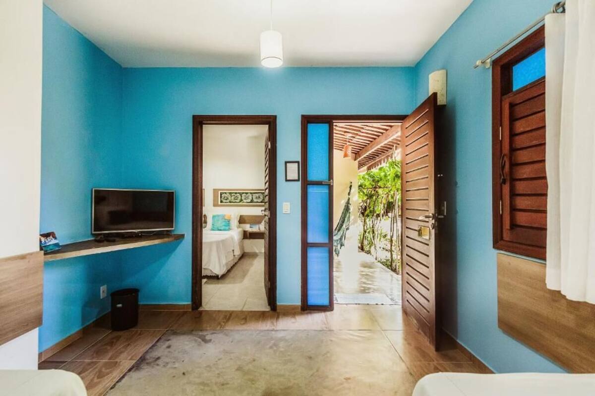 A room with a TV, a bed, and a door leading to a balcony.
