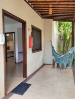 Un espacio al aire libre cubierto con una hamaca, un extintor y una puerta que da a una habitación.