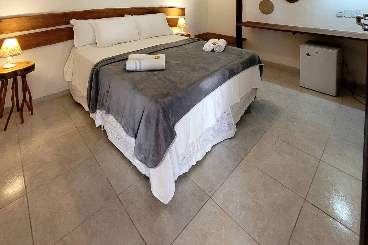 A neatly arranged hotel room with a bed, bedside lamp, and a small desk with a lamp.