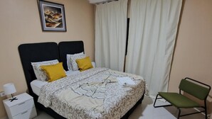 Een keurig opgemaakt slaapkamer met een bed, nachtkastje, lamp en een stoel.