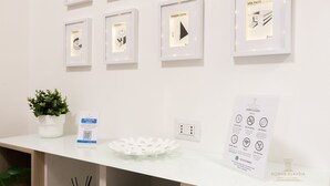 A reception desk with framed architectural drawings, a QR code sign, a potted plant, and a rules poster. - Domvs Clavdia - Metro Station, 8 min to center, A-C (Roma)