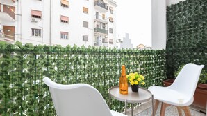 A balcony with white chairs, a small round table, and a bottle of wine. - Domvs Clavdia - Metro Station, 8 min to center, A-C (Roma)