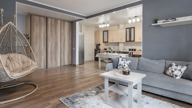 Una sala moderna con un sofá gris, una mesa de centro blanca y un sillón colgante.