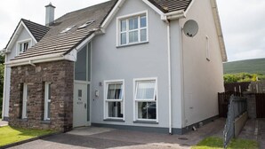 A two-story house with a stone extension, white windows, and a satellite dish.