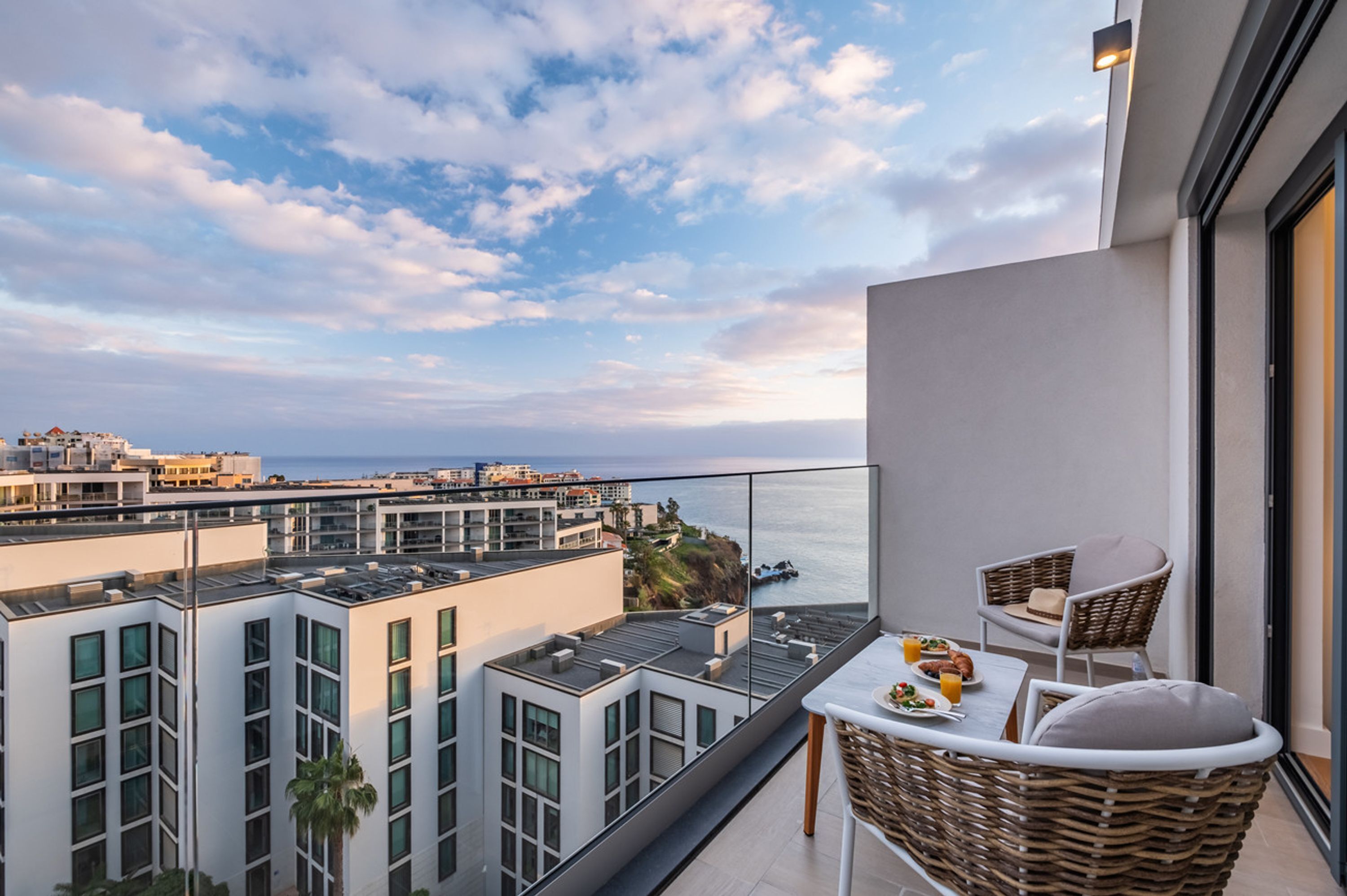 Ein Balkon mit einem Tisch für zwei Personen, mit Blick auf die Stadt und das Meer.