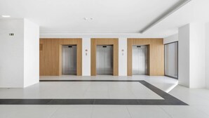 Un intérieur moderne doté de trois ascenseurs, de murs blancs et d’un sol carrelé.