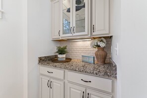 A kitchen with white cabinets, a granite countertop, and a backsplash. - New Specials! 6 Seater Cart, Bikes & Beach Toys, Gated Beach Community (SANTA ROSA BEACH)