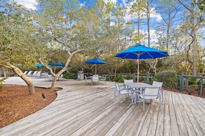 A wooden deck with outdoor seating and blue umbrellas. - New Specials! 6 Seater Cart, Bikes & Beach Toys, Gated Beach Community (SANTA ROSA BEACH)