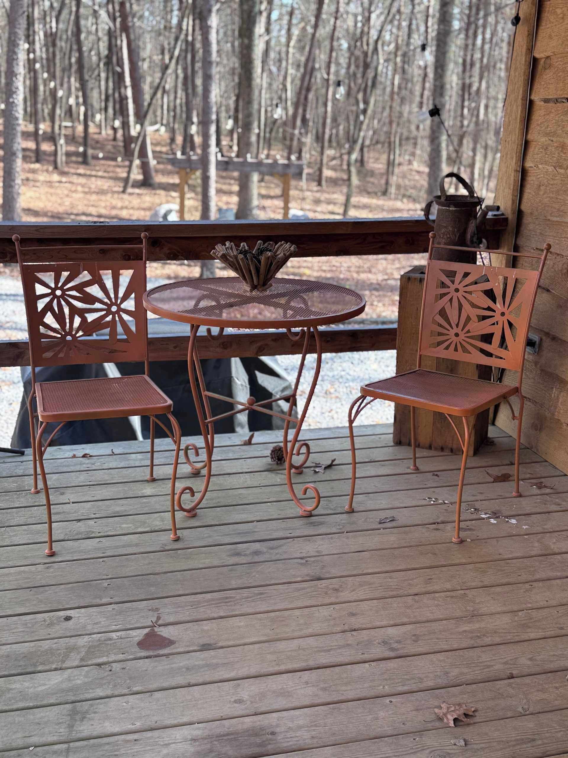 Una terraza de madera con una mesa redonda y dos sillas.