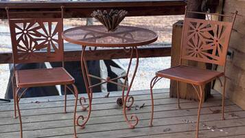 Una terraza de madera con una mesa redonda y dos sillas.