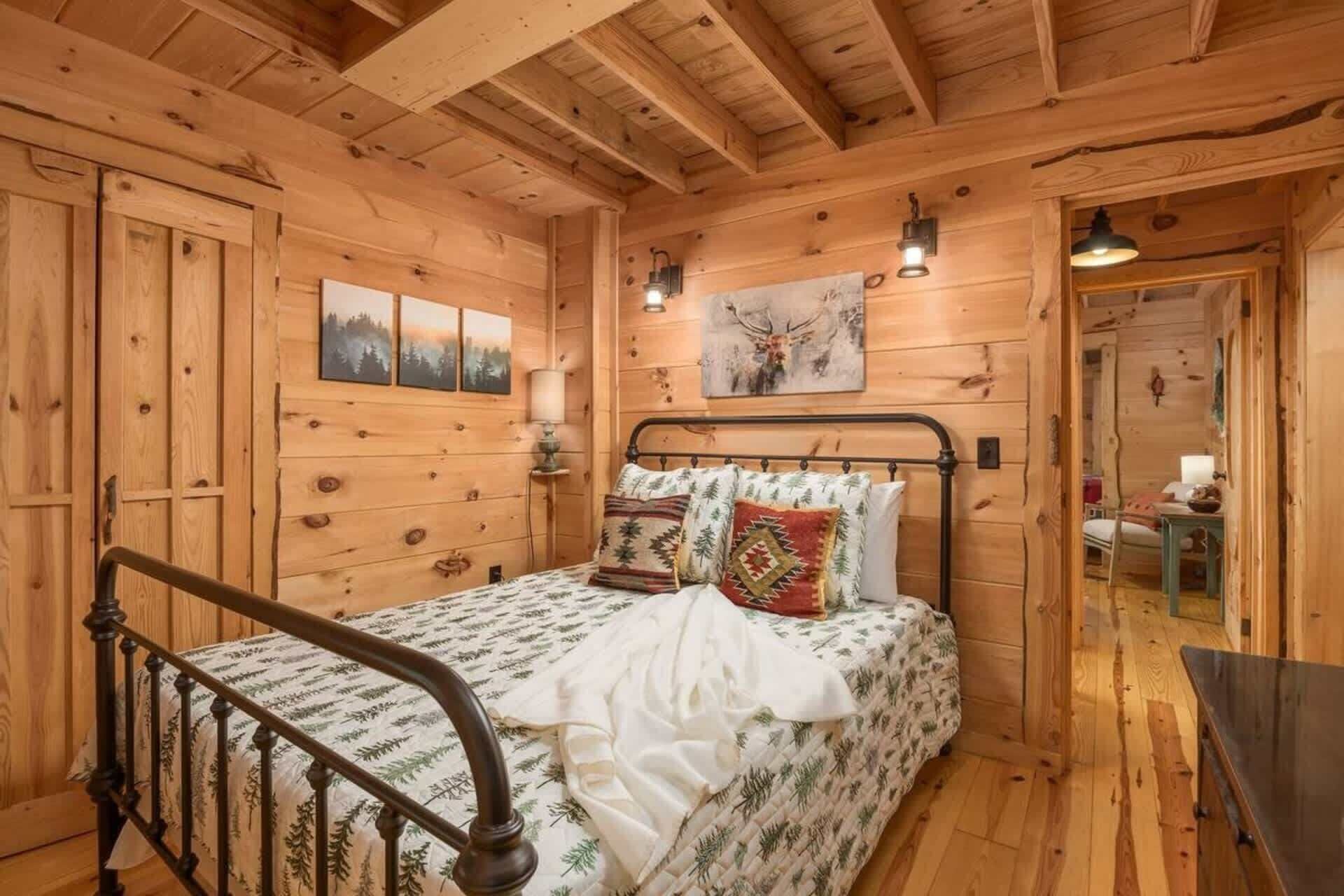 Un dormitorio de cabaña de madera con una cama, una mesita de noche y una lámpara fijada a la pared.